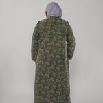 Woman wearing a green jacquard patterned abaya on a gray background