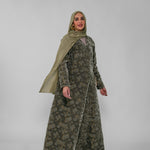 Woman wearing a green patterned abaya and matching hijab on a white background
