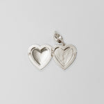 Silver heart-shaped locket on a light gray background