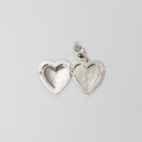 Silver heart-shaped locket on a light gray background