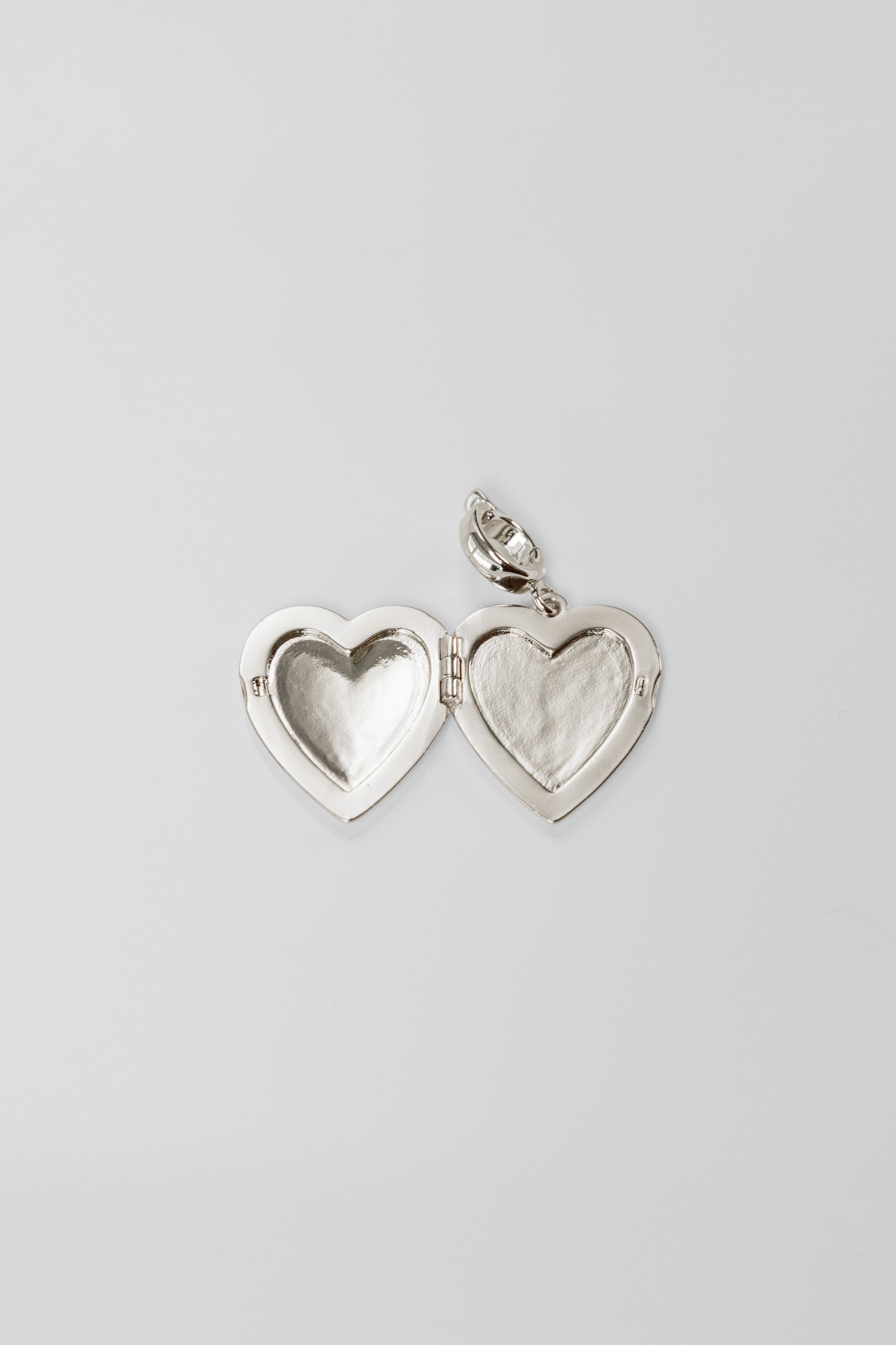 Silver heart-shaped locket on a light gray background