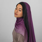 Woman wearing a purple ombre hijab against a plain background