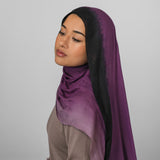 Woman wearing a purple ombre hijab against a plain background