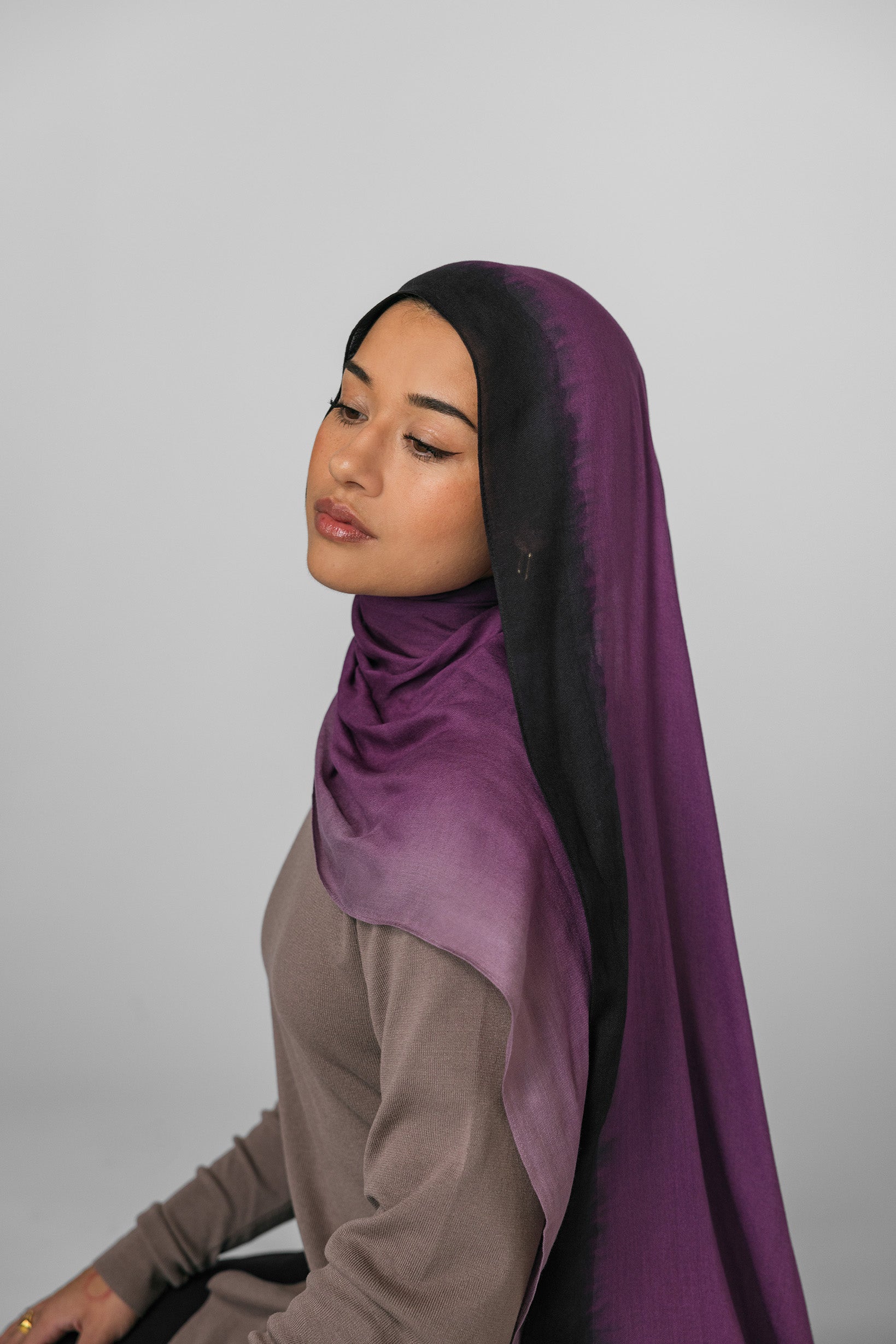 Woman wearing a purple ombre hijab against a plain background