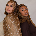 Two models shown, both wearing Fawn from VELA, a warm brown transitional print with white speckles. 