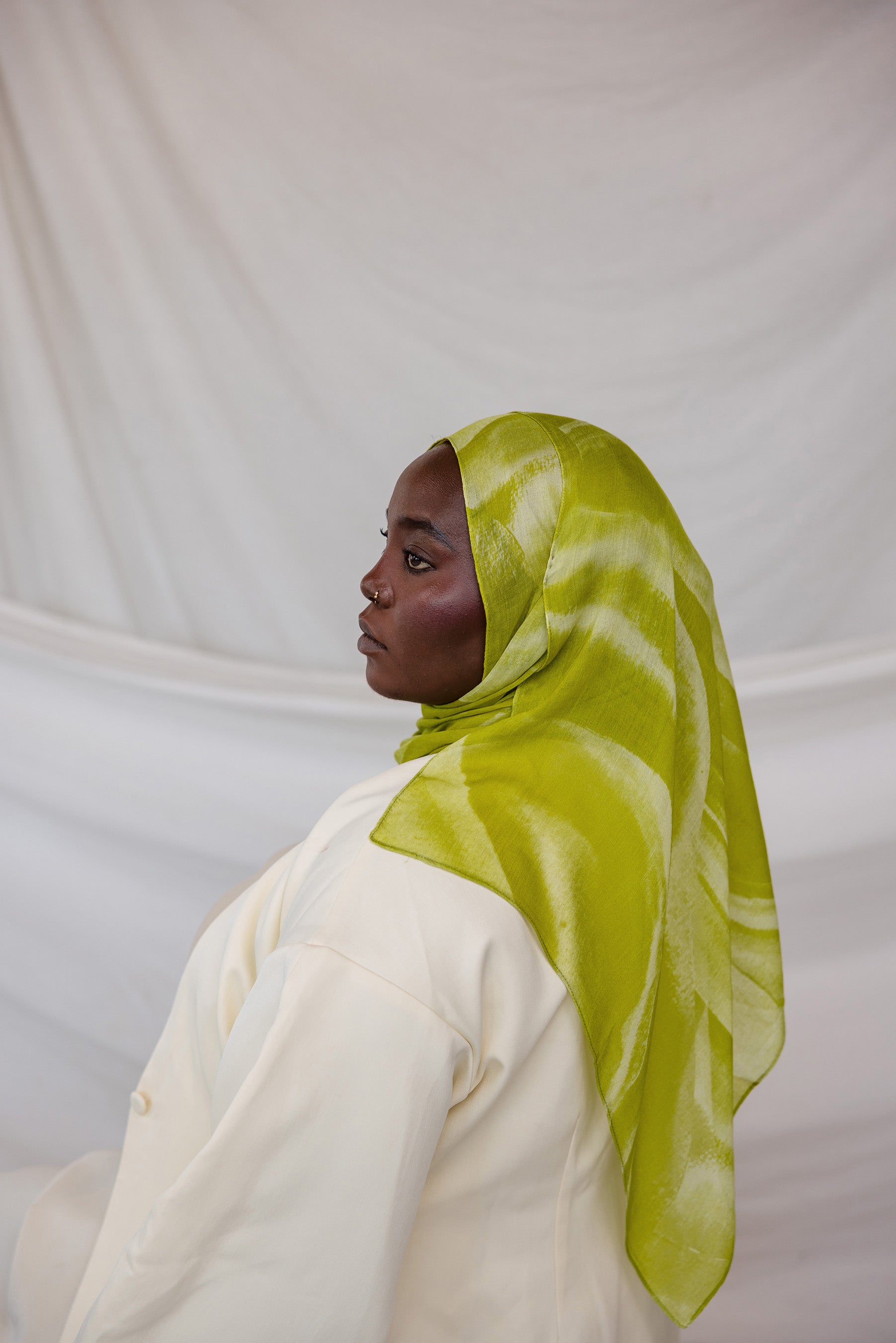 Person wearing a lime green sediment printed hijab against a white background
