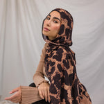 Model wearing a peach and tan based scarf with dark brown spots, called the Wild Savanna print. 