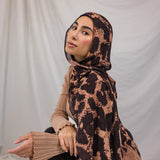 Model wearing a peach and tan based scarf with dark brown spots, called the Wild Savanna print. 