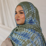 Woman wearing a green and blue Mermaid Ripple patterned hijab against a plain background