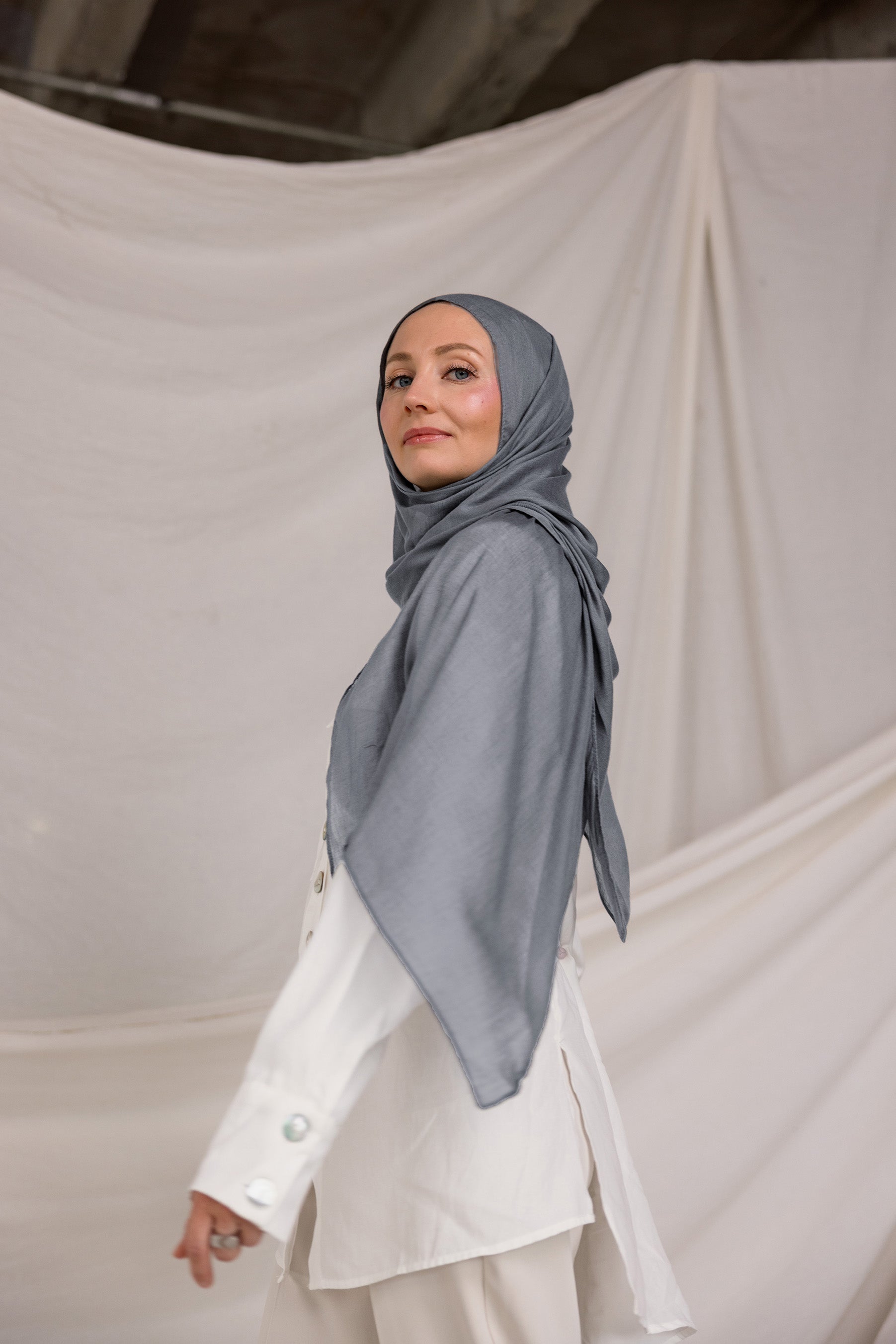 Model wearing the hijab, showing how the dark sage fabric wraps smoothly around the head and neck.