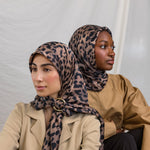 Two models styled in a silk hijab featuring a leopard print.