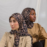 Two models styled in a silk hijab featuring a leopard print.