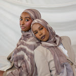 Two women wearing brown sediment printed hijabs against a white background