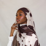 Model close-up showing the different types of brown spots on cream base of the Prairie Hide scarf. 