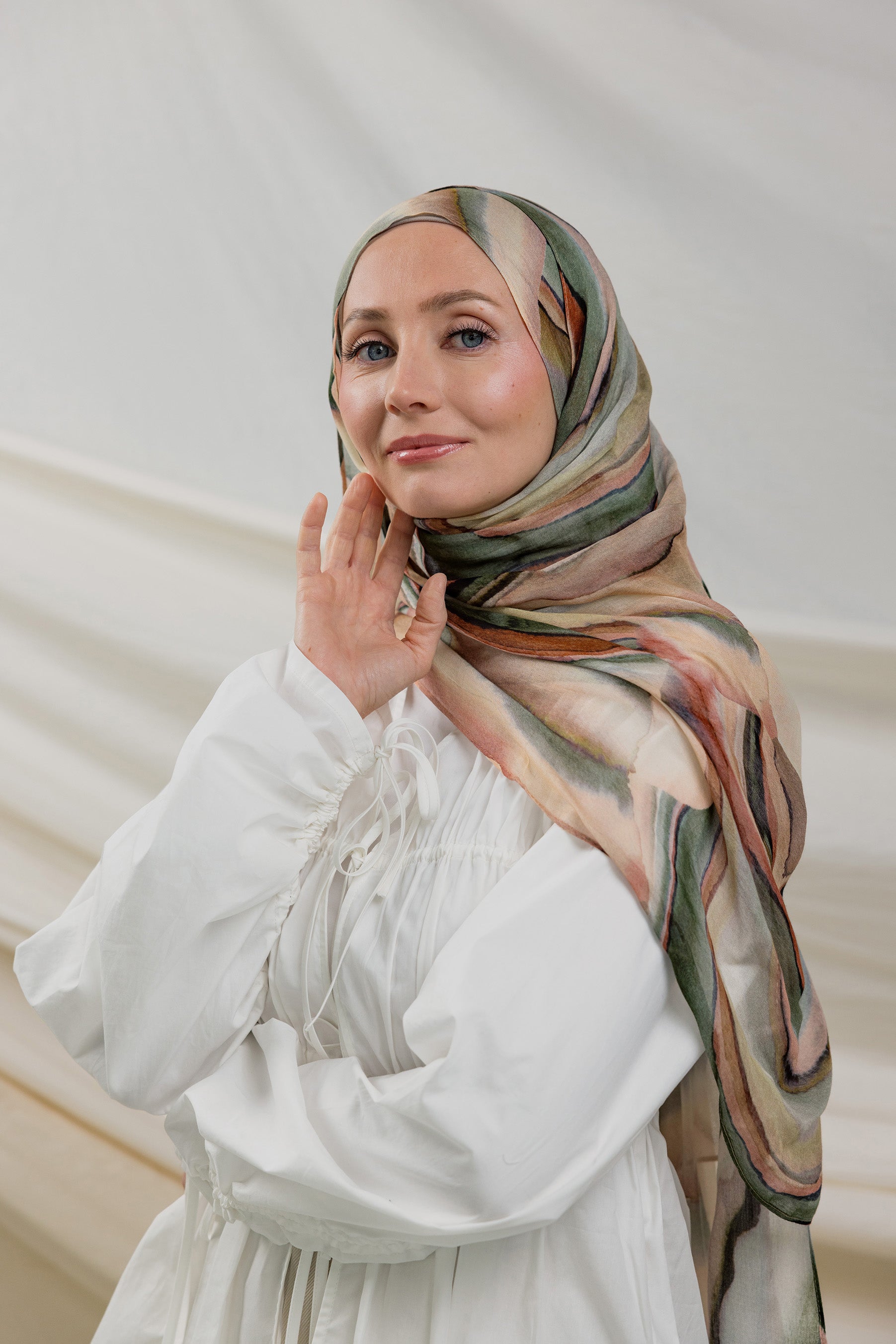 Model wearing modal hijab with a layered sediment-inspired print and artistic detailing.

