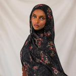 Woman wearing a dark pomegranate hijab against a plain background