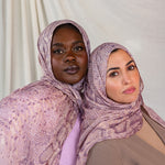 Two models posed together in pink and purple snakeskin print, styled in two different ways.