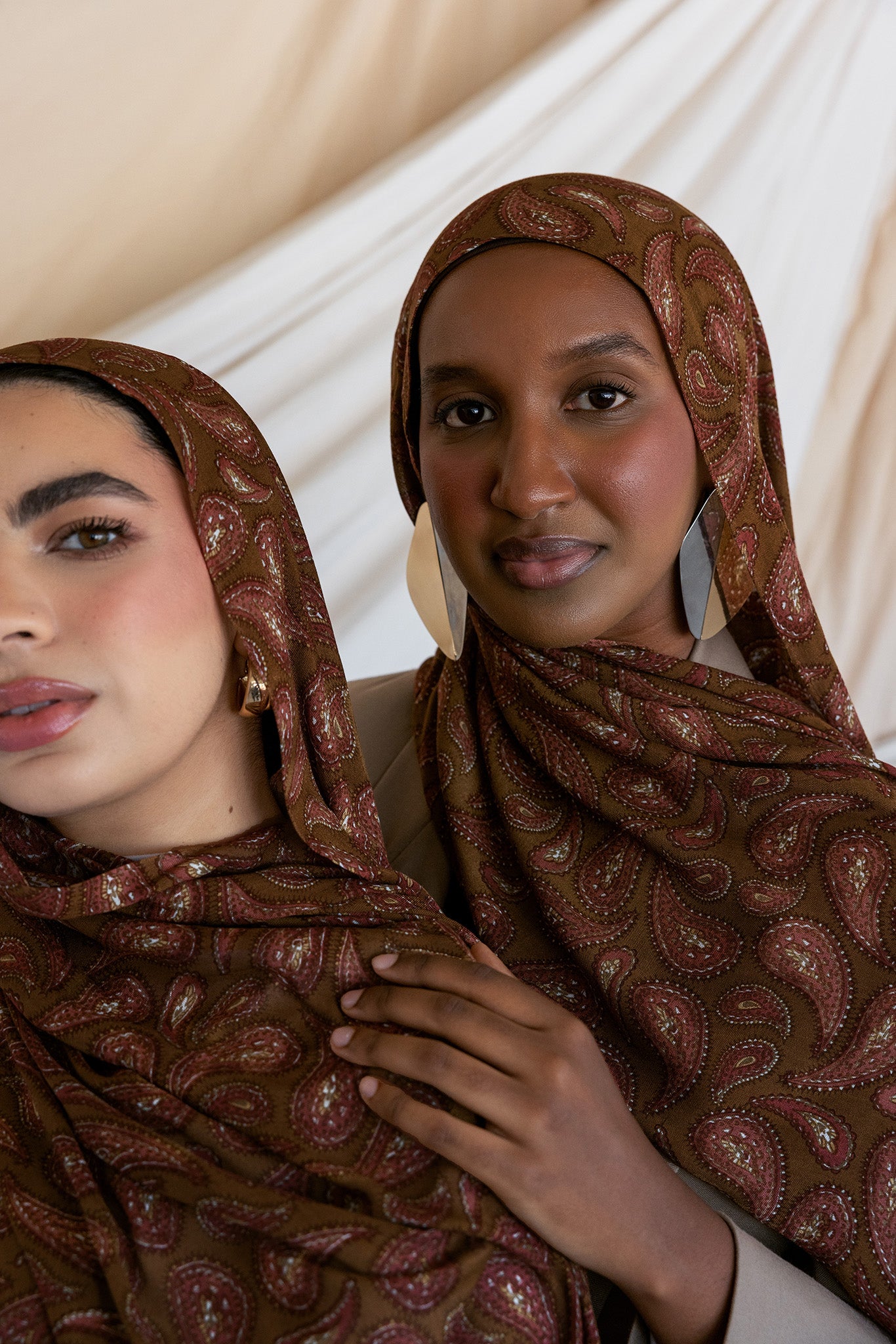 Two models styled in a brown red toned paisley print hijab. 