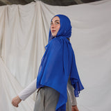 Spirulina Blue scarf pictured on model, this scarf by VELA is bright electric blue. 