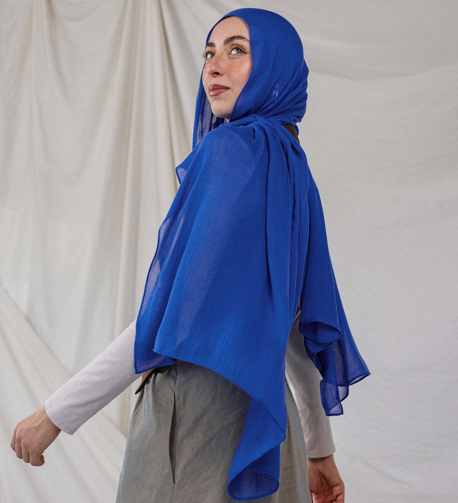 Spirulina Blue scarf pictured on model, this scarf by VELA is bright electric blue. 