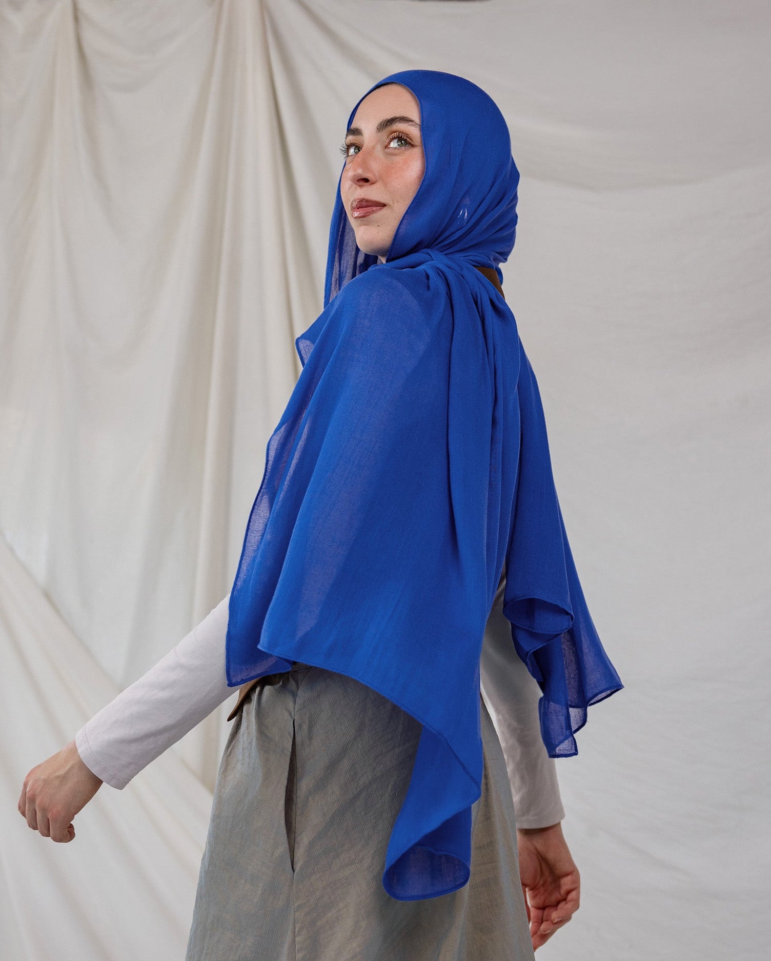 Spirulina Blue scarf pictured on model, this scarf by VELA is bright electric blue. 
