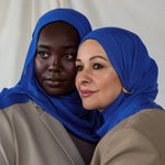 Close-up of Spirulina Blue on two models that shows the tone of the scarf - a vivid and saturated electric blue. 