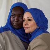 Close-up of Spirulina Blue on two models that shows the tone of the scarf - a vivid and saturated electric blue. 