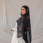 Woman wearing a dark pomegranate print hijab against a plain background