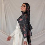 Woman wearing a black pomegranate hijab against a plain background