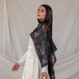 Woman wearing a black pomegranate hijab against a plain background