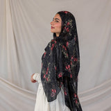 Woman wearing a black pomegranate printed hijab against a plain background