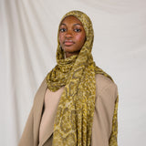 Model posing in Golden Cobra, a golden/yellow snakeskin print scarf. 