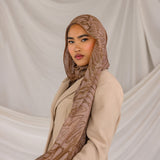 Woman wearing a brown dune hijab and beige outfit against a plain background