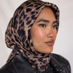 A woman wearing a leopard printed silk hijab. 