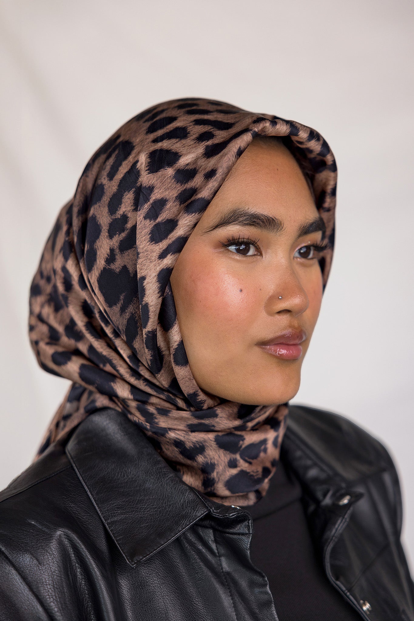 A woman wearing a leopard printed silk hijab. 