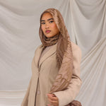 Woman styled in a Mocha Dunes printed hijab wearing a beige coat against a plain background.