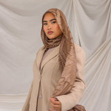 Woman styled in a Mocha Dunes printed hijab wearing a beige coat against a plain background.