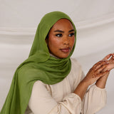 Model wearing the Fern Green hijab styled simply, captured from a side angle with a soft studio background.