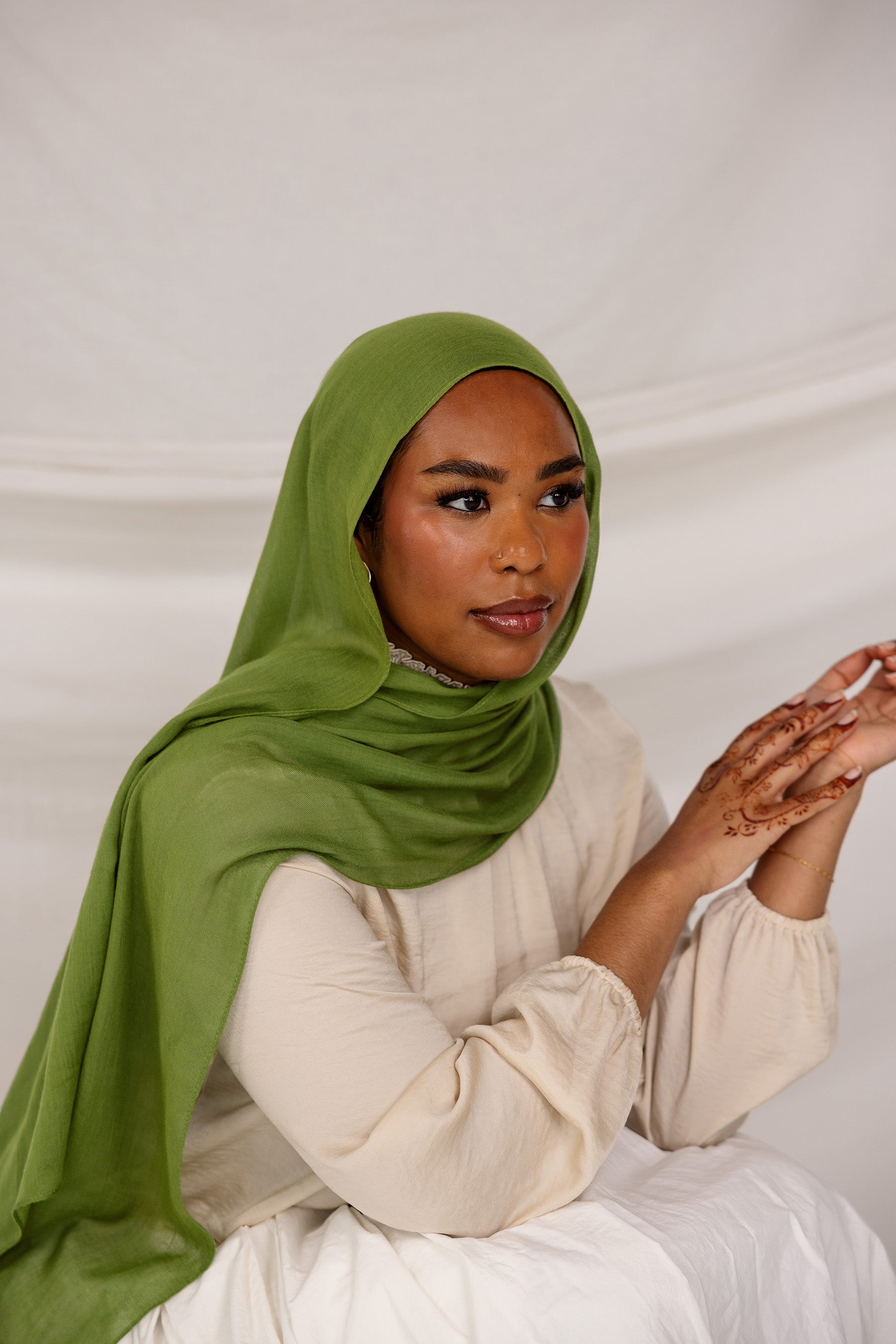 Model wearing the Fern Green hijab styled simply, captured from a side angle with a soft studio background.