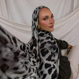 Woman wearing a leopard print hijab against a white draped background