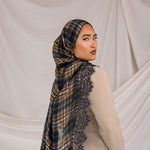 Woman wearing a black orange plaid scarf with lace details on a plain background