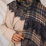 Person wearing a plaid scarf with lace details on a neutral background