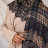 Person wearing a plaid scarf with lace details on a neutral background