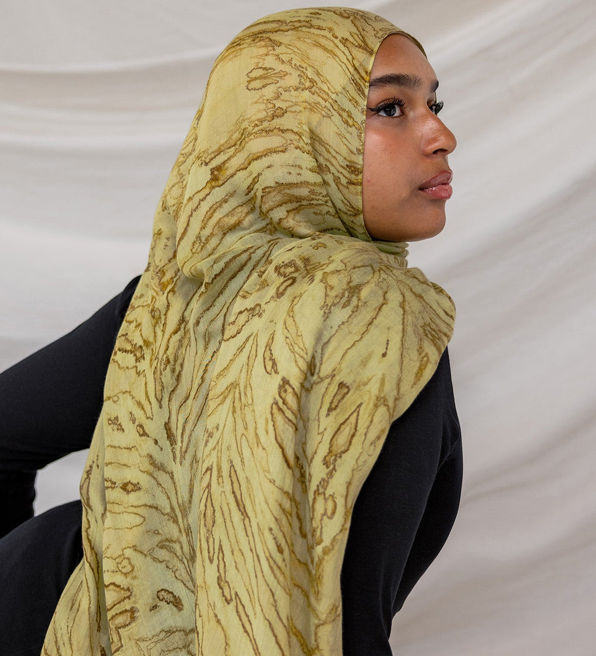 Woman wearing a olive printed dune hijab against a white background