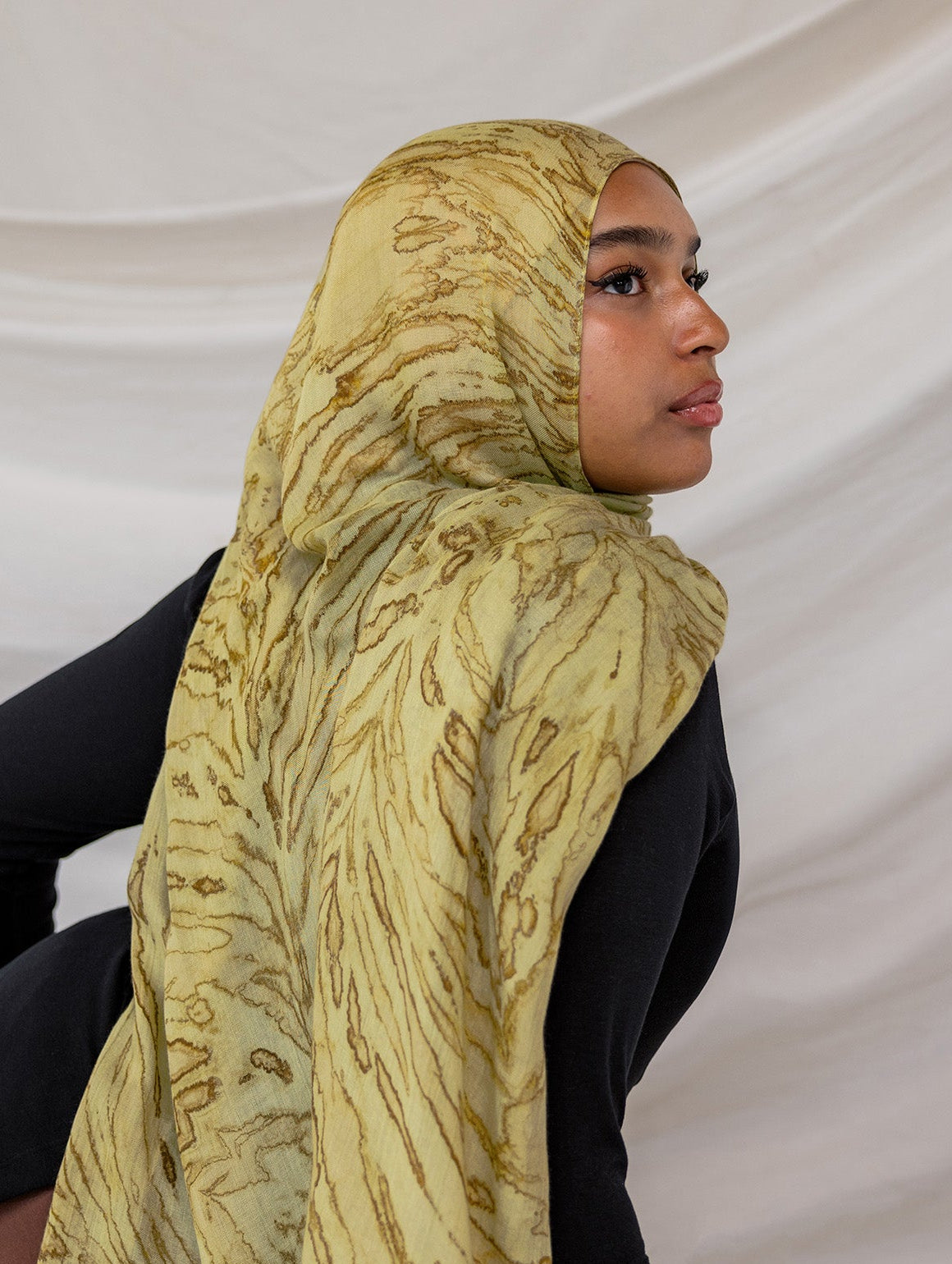 Woman wearing a olive printed dune hijab against a white background