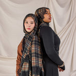 Two women wearing hijabs with plaid patterns against a plain background