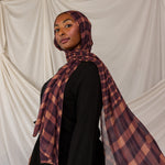 Woman wearing a plaid hijab in front of a white curtain