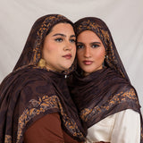 Sister models in Chocolate Paisley hijabs holding each other posed together in studio light.