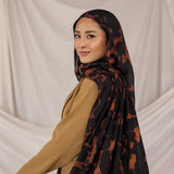 Model wearing a black and brown tortoiseshell patterned hijab against a plain background