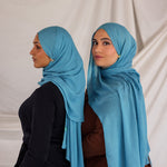 Two models styled in bright blue hijabs against a plain background